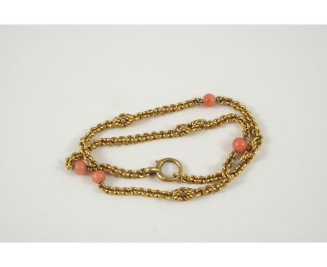 A GOLD AND CORAL NECKLET the gold chain with knot links and mounted with coral beads, 35cm. long, 25 grams.