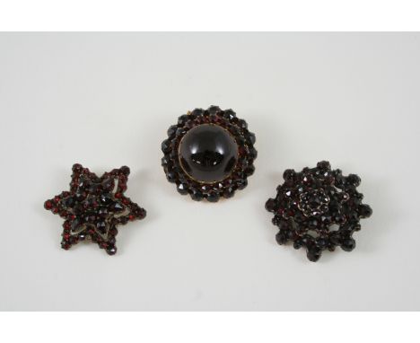 A VICTORIAN GARNET BROOCH centred with a circular cabochon garnet within a surround of circular faceted garnets, in gilt meta