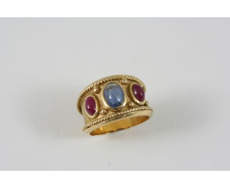 A GOLD AND GEM SET RING the gold band is set with a cabochon sapphire and two cabochon rubies. Size N.