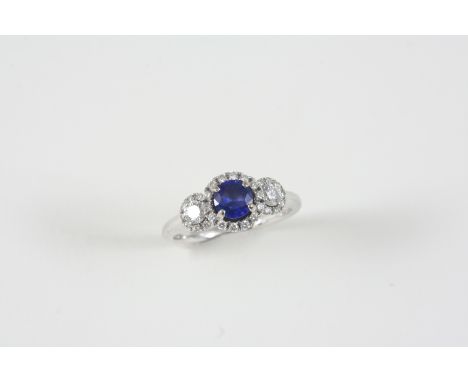 A SAPPHIRE AND DIAMOND TRIPLE CLUSTER RING centred with a circular-cut sapphire within a surround of small diamonds, with two