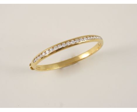A DIAMOND AND GOLD HINGED BANGLE the 18ct. gold bangle is set with brilliant-cut diamonds to one side, weighing approximately