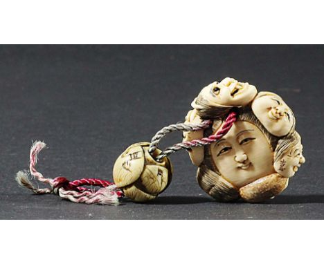 JAPANESE IVORY NETSUKE, late 19th century, carved with a double sided face surrounded by six masks, signed, diameter 4cm; wit