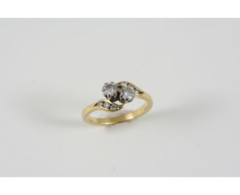 A DIAMOND CROSS-OVER RING the two circular-cut diamonds are set with three small diamonds to each shoulder, in gold. Size M 1