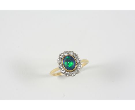 A BLACK OPAL AND DIAMOND CLUSTER RING the oval-shaped solid black opal is set within a surround of twelve old brilliant-cut d