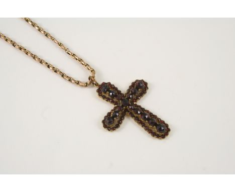 A VICTORIAN GARNET CRUCIFORM PENDANT set with graduated circular faceted garnets in gilt metal, 4 x 3cm., on a 9ct. gold chai