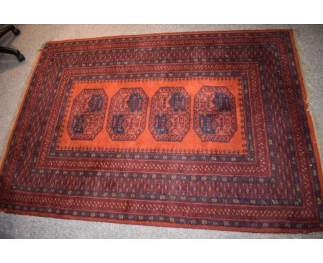 A vintage middle-eastern / Afghan Bokhara rug / carpet in the Elephants Foot pattern. Colours deep reds, blues and oranges. 1