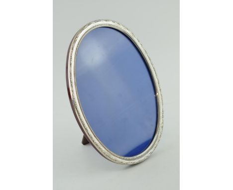 Large silver oval photo frame, mahogany easel back, 27cm tall.
