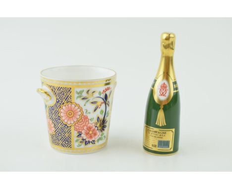 A Royal Crown Derby miniature Champagne bottle together with a two handled cup. Height 9cm. (2) Of first quality free of rest