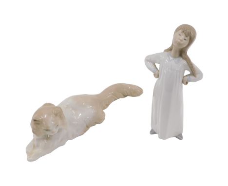 A Lladro porcelain figure of a young girl in a nightdress, and a Nao figure of a cat. (AF)