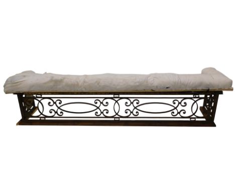 A late 19th/early 20thC wrought iron Waring &amp; Gillow club fender, with scroll design, sold with some later padding, mould