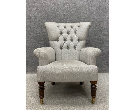 A 19th century button back library armchair having a tapered back with scrolling arms over a serpentine fronted stuffover sea