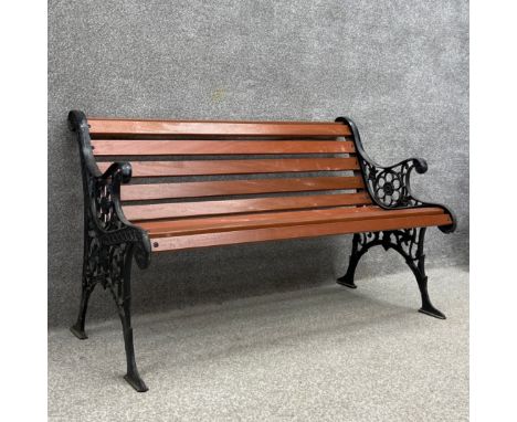 A contemporary 19th century style garden bench with scrolling openwork cast iron ends united by teak slats raised on splayed 