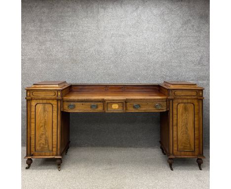A large Regency twin pedestal drop centre walnut sideboard in three parts having a satinwood strung gallery back above a bow 