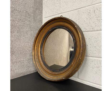 A Regency circular mirror having a convex plate in an ebonised slip border within a giltwood surround. H.70 W.66cm 