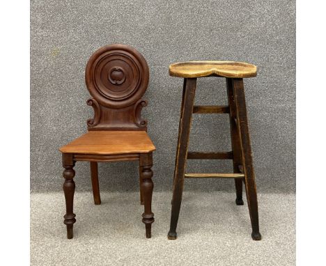 A mid 19th century mahogany hall chair having a circular carved back with scrolling decoration over a serpentine fronted plan