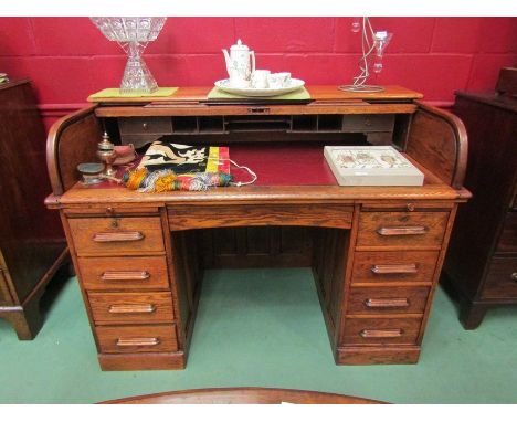 An Edwardian panelled oak tambour front twin pedestal desk the fitted interior over a central kneehole drawer and brushing sl