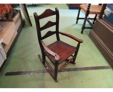 Circa 1800 an oak child's rocking chair the three rung ladder back rest with handpainted floral decoration on turned legs and