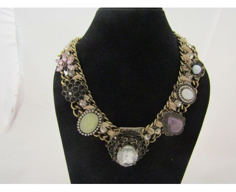 A vintage yellow metal necklace with a row of clear glass stones and central mounted cut example, velvet backed 