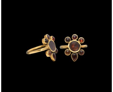 5th-6th century AD. A gold finger ring with round-section hoop with central circular bezel flanked by five smaller round cell
