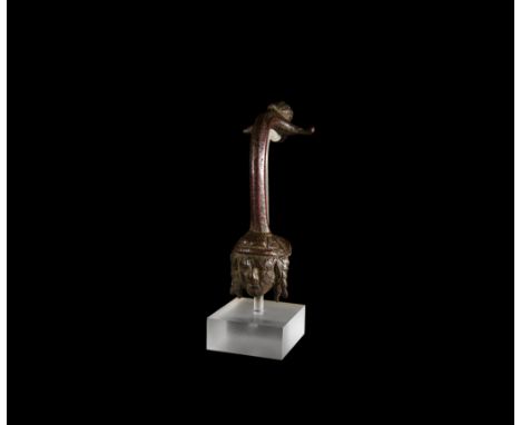1st century BC-1st century AD. A bronze ewer handle, facetted and gently curved at the top; the lower finial a facing mask of