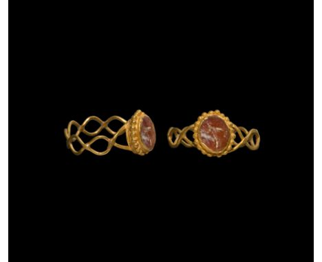 1st century AD. A gold finger ring with twisted wire hoop supporting an oval-shaped bezel with a border of granulated beads, 