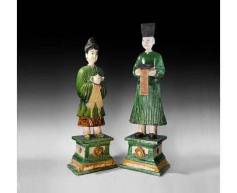 Ming Dynasty, 1368-1644 AD. A mixed pair of three-part ceramic attendant figures, each standing on a tiered base with rosette