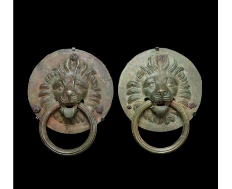 1st-3rd century AD. A matching pair of substantial bronze door knockers or furniture handles, each a discoid plaque with a ce