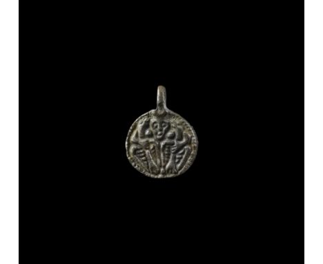 9th-10th century AD. A discoid silver pendant with integral loop, border enclosing a low-relief image of a male facing mask b