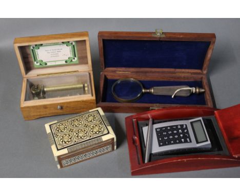 Four wooden boxes, 1 containing a calculator, 1 a magnifying glass, music box and playing cards