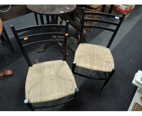 A pair of 20th Century ebonised frame Aesthetic style chairs by ladder backs with rush seats and tapered legs