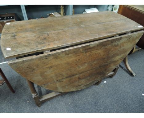 A late 19th century oak dining table in the 18th century style, having oval drop leaf top on turned gate legs