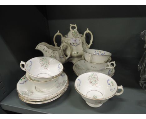 A vintage tea service un marked with enamel hand decorations includes tea cups saucers tureen and jug