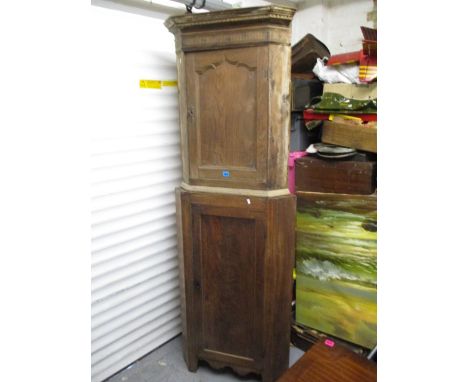 An early 20th century mahogany corner cabinet, the top with a dentil moulded cornice, above a shaped, arched fielded door, be