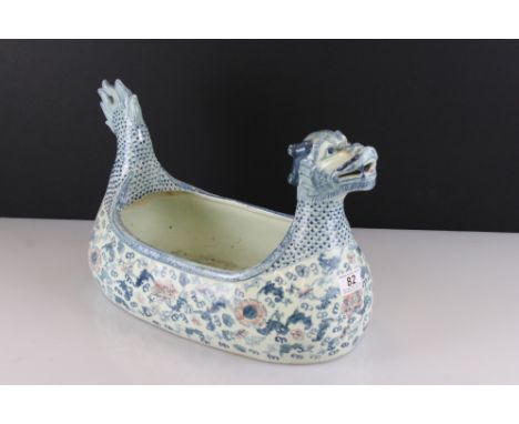 A large ceramic planter in the form of a dragon with blue floral decoration. 