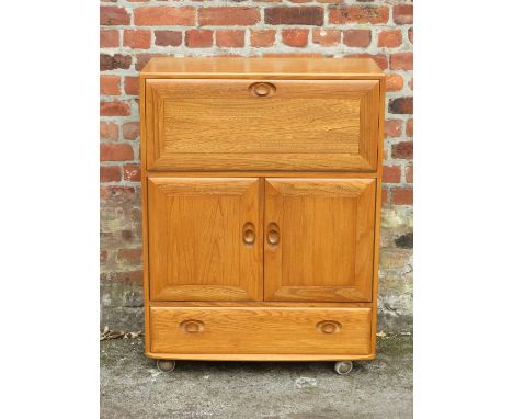 An Ercol light elm cocktail cabinetHaving single pull down door enclosing shelf, above two panelled cupboard doors and single