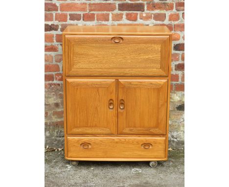 An Ercol light elm cocktail cabinetHaving single pull down door enclosing shelf, above two panelled cupboard doors and single