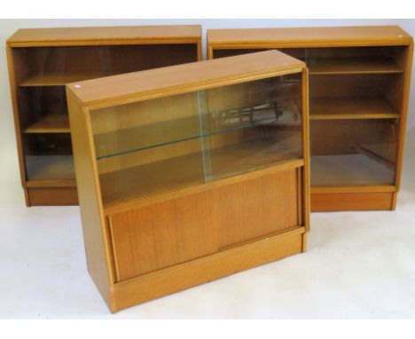 Three Mid Century light oak bookcasesEach of sloped form with two sliding glass doors above panelled cupboard doors, height 8