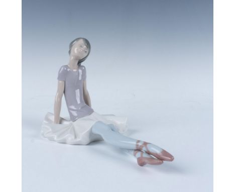 A glossy figure of a sitting ballerina with a joyful smile. This item has its original box, measuring 12.5"L x 10.25"W x 6"H.
