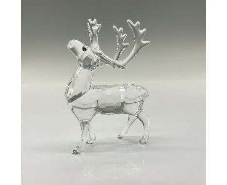 A clear crystal figure of a reindeer with large antlers and his head facing upwards. Melon colored crystal used for the eyes.