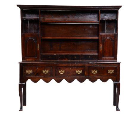 A George III oak dresser, the cavetto cornice above two-shelf boarded rack with spice cupboards with arched raised and fielde