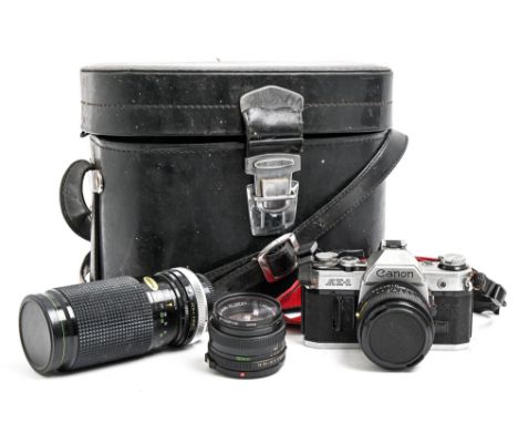 A Canon AE-1 35mm single lens reflex camera and maker's 50mm F1.8 and 28mm F2.8 lenses and another lens  The collection of C.