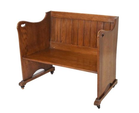 20th Century oak settle or pew, the planked rectangular back flanked by shaped sides with pierced carrying handles on sled ba