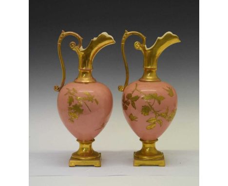 Pair of late 19th Century parcel gilt ceramic ewers, each worked with foliage, birds and butterflies on a pink ground, 40cm h