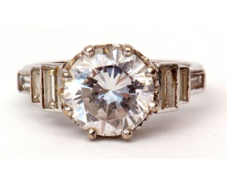 Precious metal paste and diamond ring, having a large brilliant white central stone raised between baguette diamond shoulders