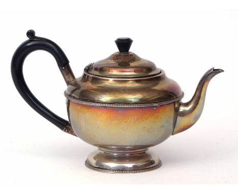 George V tea pot of circular form with hinged and domed cover on a spreading circular foot and with composite finial and hand