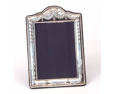 Elizabeth II silver mounted easel backed photograph frame of shaped rectangular form, the mount with swag and ribbon detail t