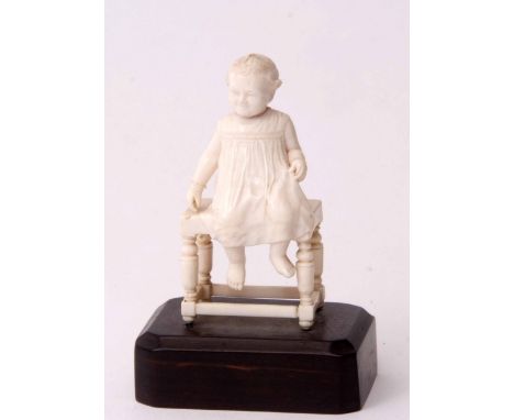 Early 20th century carved ivory model of a young child sitting upon a bobbin turned joint stool and raised on a rectangular h