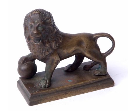 Cast brass model of a standing lion with right paw atop a sphere on a rectangular base, width 8 1/2 cms 