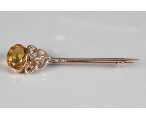 9 carat yellow gold stick pin with Celtic decoration leading to a mounted citrine, 9.5cm long.  Inverness maker: William B Ta