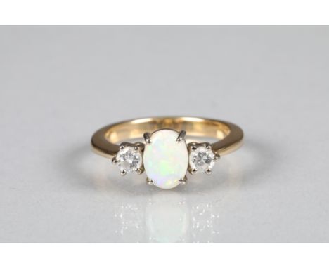 Ladies diamond and opal ring with central opal flanked by a single diamond on either side on yellow metal shank, each diamond